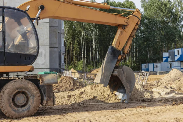 挖掘机在基坑上挖一个基坑 以便建造一座住宅大楼 背景中的新住宅建筑 建筑生产 — 图库照片