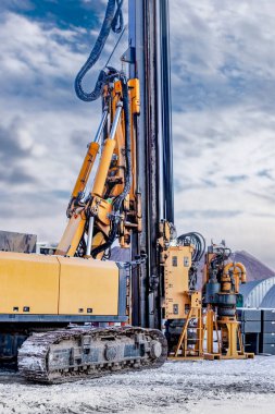 İnşaat alanında kışın kazık kazmak için güçlü bir sondaj kulesi. Sondaj kulesinin kuzey koşullarında çalışması. Yığın vakıfları. Sıkıcı yığınlar. Yakın plan.