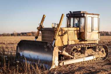 Akşamları bir inşaat sahasında, günbatımının arka planında çalışan güçlü bir buldozer. Toprak işçiliği için inşaat ekipmanları