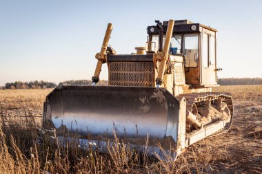 Akşamları bir inşaat sahasında, günbatımının arka planında çalışan güçlü bir buldozer. Toprak işçiliği için inşaat ekipmanları