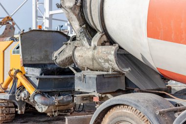 Beton karıştırıcı bir kamyon inşaat alanında beton bir pompaya havan topu döker. Monolitik güçlendirilmiş beton işlerinin üretimi için beton ve harç tedariği. Yakın plan.