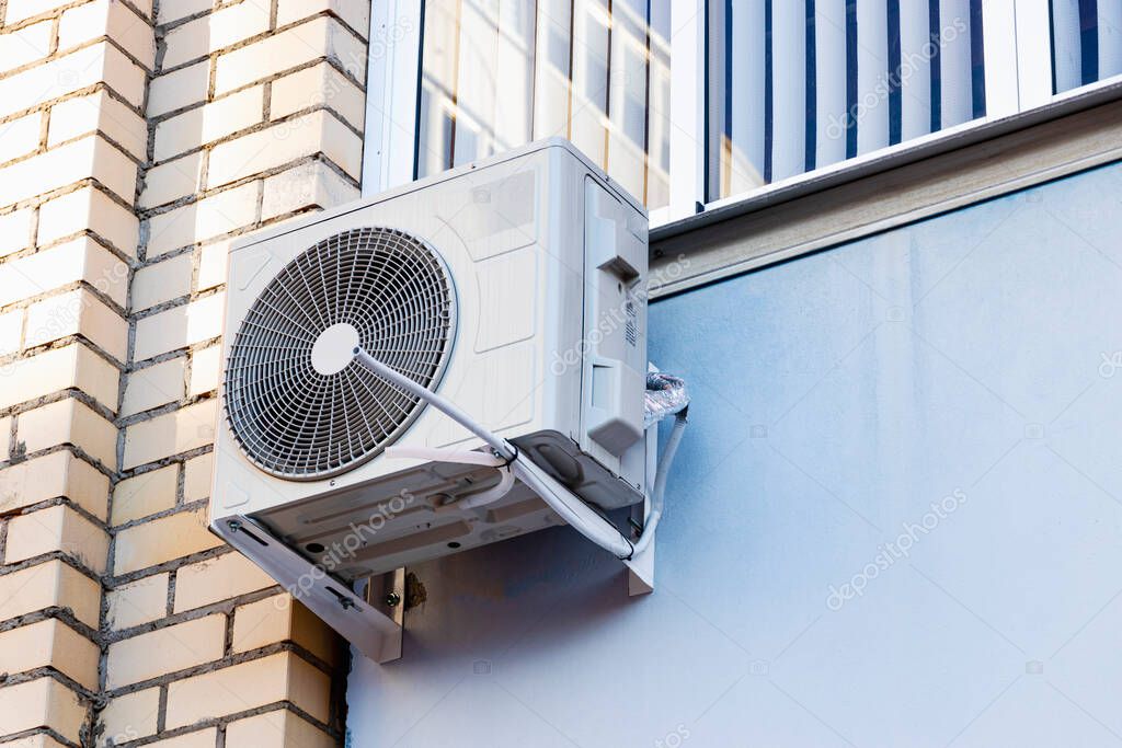 An air conditioning system installed outside on the wall of a brick building. Ventilation and air conditioning of housing