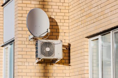 Dışarıdaki tuğla binanın duvarına bir havalandırma sistemi yerleştirilmiş. Uydu anteni. Konutların havalandırması ve havalandırması. TV sinyali