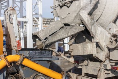 Beton karıştırıcı bir kamyon inşaat alanında beton bir pompaya havan topu döker. Monolitik güçlendirilmiş beton işlerinin üretimi için beton ve harç tedariği. Yakın plan.