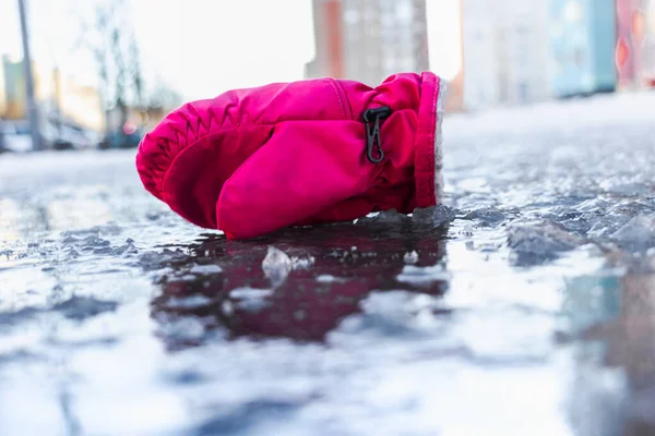 氷で作られた滑りやすい道に子供のミトン 春の解凍と氷 市内の冬の道路 氷の道に落ちた後の怪我と結果 — ストック写真