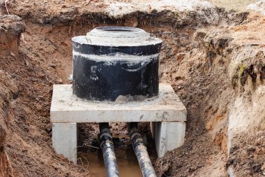 İnşaat alanına su ve kanalizasyon için güçlendirilmiş beton kuyusu kurulması. Demir kapaklı ve inşaat aletli halkalar.