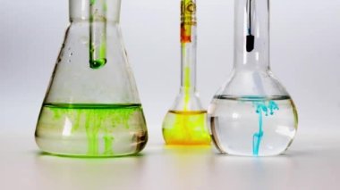 Beyaz arka planda sıvı yakın plan laboratuvar mataraları. Tıbbi laboratuvar araştırmaları ve analizleri. Farklı renkte ayıraçlar.