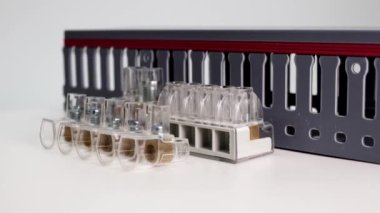 Beyaz arka planda elektrik terminali blokları ve dağıtım blokları. Farklı voltajların elektrik kablolarını bağlıyorum. Elektrik kablolarını döşemek için kanal. Elektrikçi. Yakın plan..