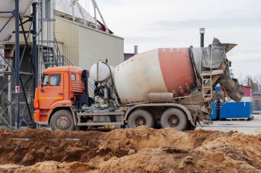 Beton karıştırıcı kamyon fabrikaya beton yüklüyor. İnşaat alanına beton nakli. Beton teslimatı için inşaat ekipmanları