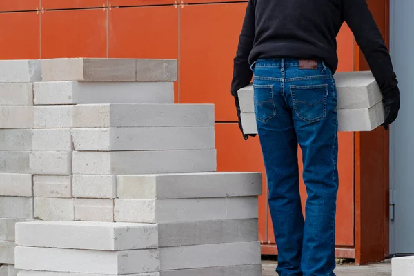 男は建設現場に泡コンクリートブロックを運びます 建設作業のための準備 住宅内の壁の建立 — ストック写真