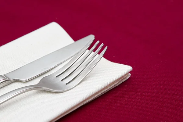 Messer und Gabel mit weißer Serviette auf rot — Stockfoto