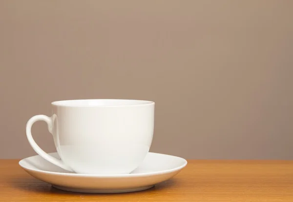 Witte kop en schotel op houten tafel — Stockfoto