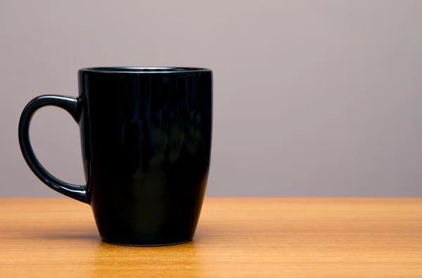 Zwarte koffiemok op houten tafel — Stockfoto