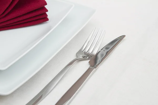 Place setting with white plates and red folded napkin — Stock Photo, Image