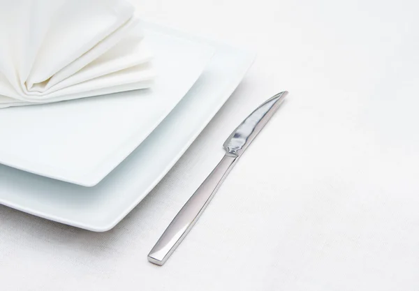 Ajuste de lugar blanco con cuchillo y servilleta blanca plegada — Foto de Stock