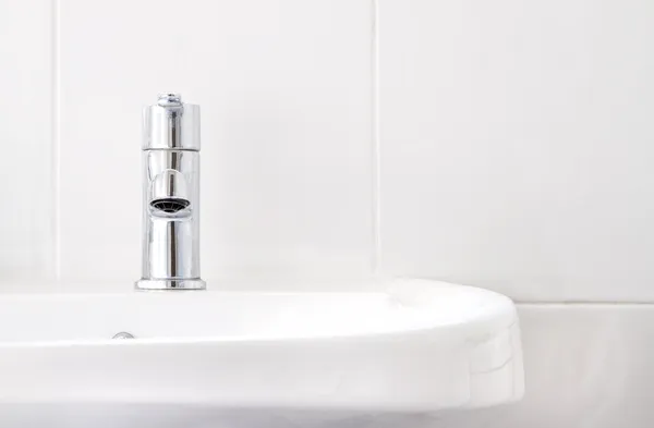 Un robinet sur lavabo blanc avec carreaux blancs Images De Stock Libres De Droits
