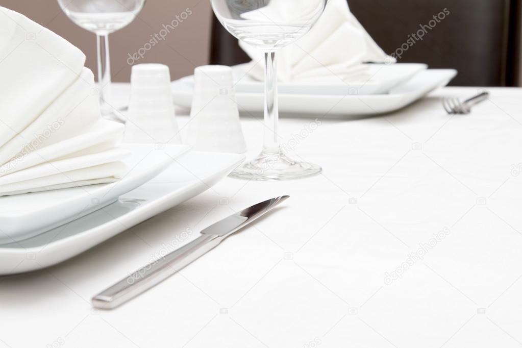 Place setting with white plates and wine glasses