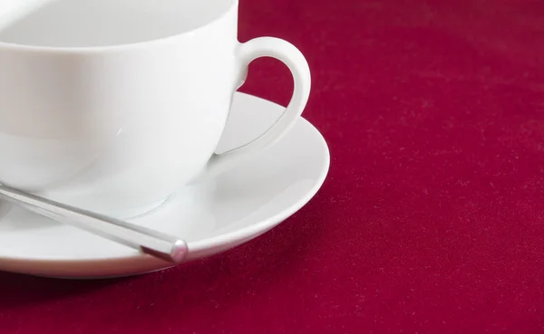 Witte kop en schotel op rood tafellaken — Stockfoto