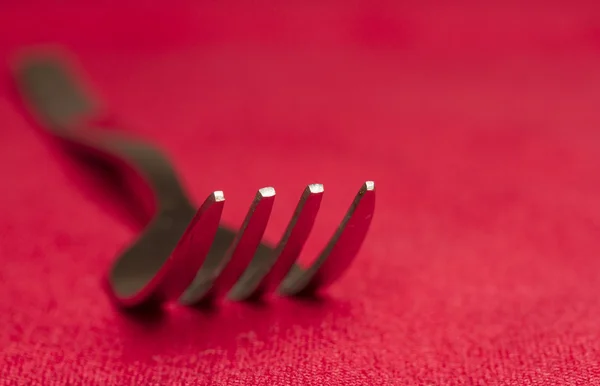 Tenedor de comedor de metal sobre fondo rojo profundidad superficial del campo — Foto de Stock