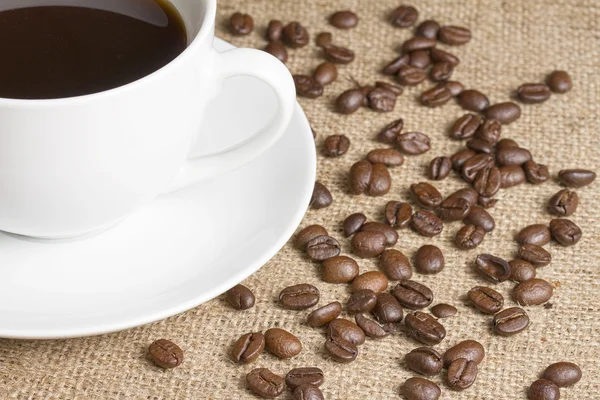 Kopje zwarte koffie met bonen op Hessiaan — Stockfoto