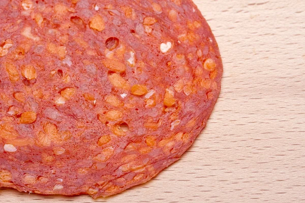 Slice of chorizo sausage on wooden chopping board — Stock Photo, Image