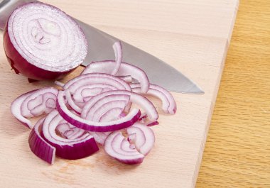 Kırmızı soğan yarım kıyılmış dilimleri ve ahşap blok üzerinde bıçak ile