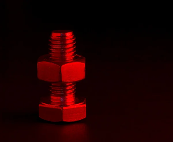 Tuerca y perno con iluminación roja sobre negro — Foto de Stock