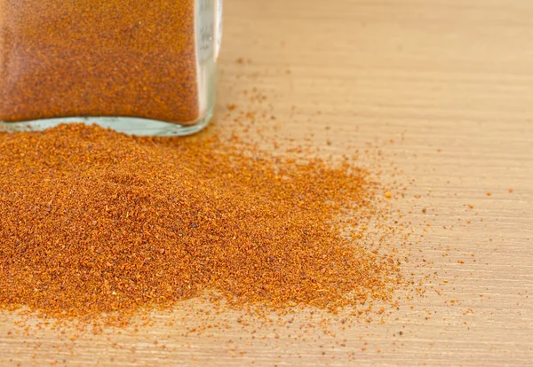 Pile of dried paprika with glass jar on wooden worktop — Stock Photo, Image