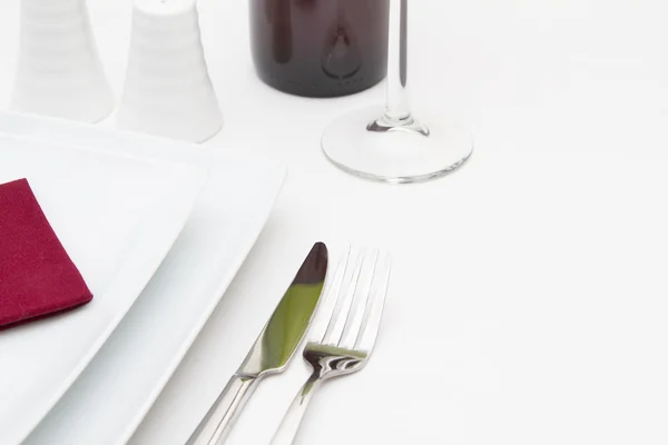 Place setting with white plates and red wine bottle — Stock Photo, Image