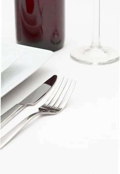 Place setting with white plates and red wine on white cloth — Stock Photo, Image