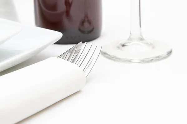 Placez le réglage avec des assiettes blanches, du verre et du vin rouge sur du tissu blanc — Photo