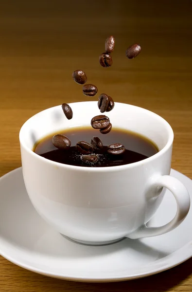 Kopje zwarte koffie met koffiebonen — Stockfoto