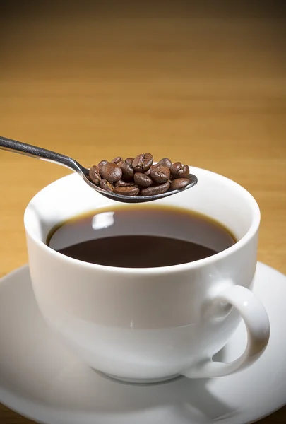 Kopje zwarte koffie met lepel van koffie bonen — Stockfoto