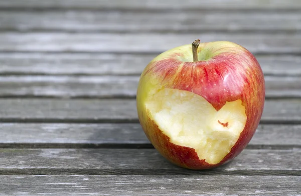 Part eaten ripe apple on wooden boards — Stock Photo, Image
