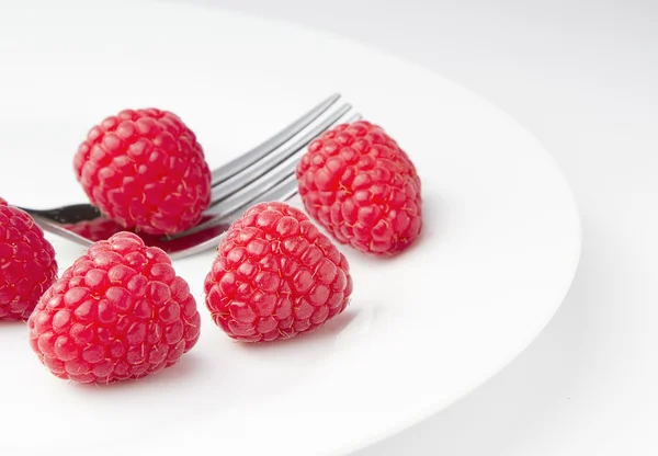 Frambuesas rojas maduras en un plato con un tenedor —  Fotos de Stock