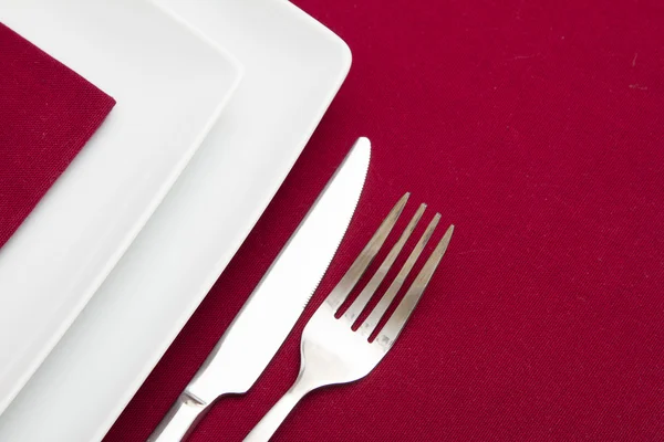 Red tablecloth with white square plates and red napkin — Stock Photo, Image