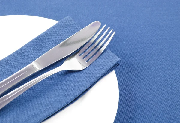 Cutlery with white plate on blue napkin — Stock Photo, Image