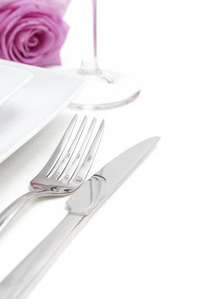 夕食の場所の設定。フォーク、ナイフ、グラス、ピンクのバラと白い陶磁器の版 — ストック写真
