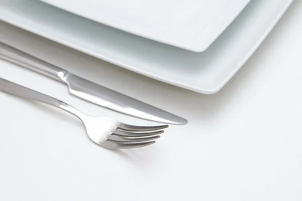 Place setting. white china plates with silver knife and fork — Stock Photo, Image