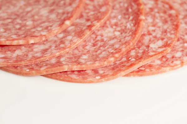 Several slices of salami on a white plate — Stock Photo, Image