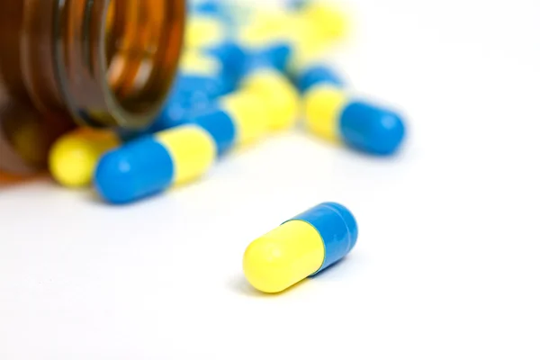Yellow and blue pills with brown bottle — Stock Photo, Image