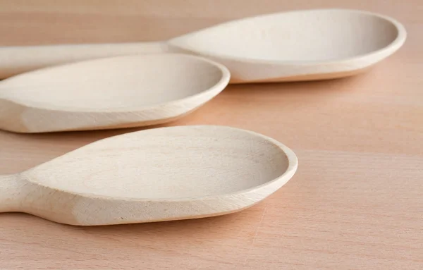 Three wooden spoons on a kitchen chopping board — Stock Photo, Image