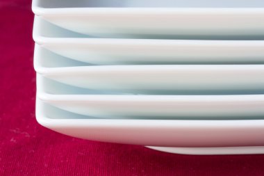 kırmızı masa örtüsü üzerinde beyaz tabak yığını