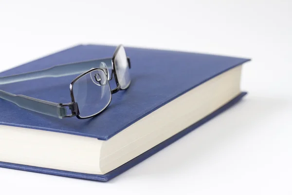 Spectacles on a blue closed book — Stock Photo, Image