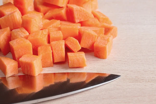 Diced raw carrots with knife on a chopping board — Stock Photo, Image