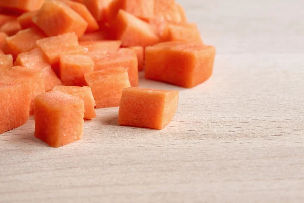 Diced raw carrots on a wooden chopping board — Stock Photo, Image