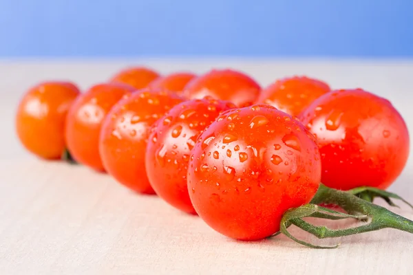 Tomates mûres de vigne cerise sur une table avec fond bleu ciel — Photo