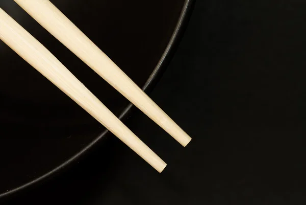 Two chopsticks on top of a black bowl — Stock Photo, Image