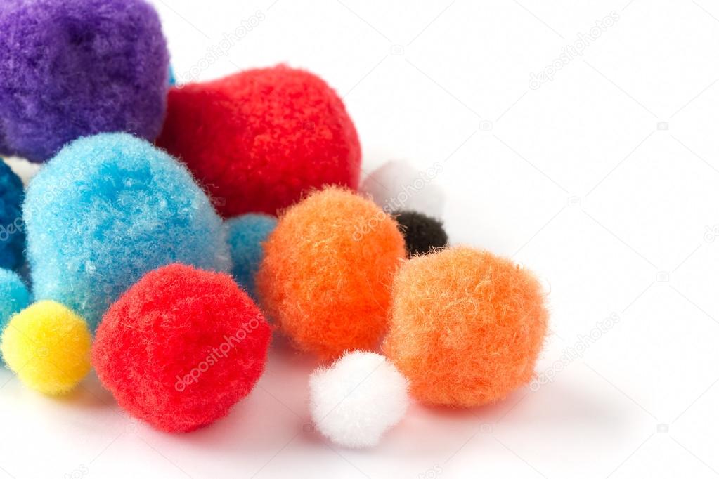 Colorful fluffy pom poms on a white background