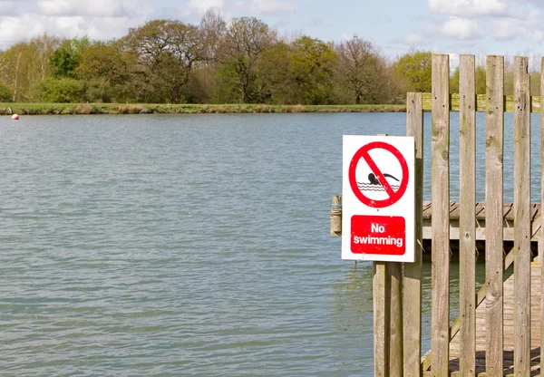 No swimming sign on jetty at edge of lake — Stock Photo, Image